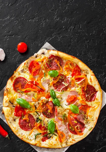Pizza Mozzarella peyniri, jambon, domates, salam, biber, biber baharat ve taze fesleğen. İtalyan pizza.on siyah arka plan. kopya alanı ile. üstten görünüm
