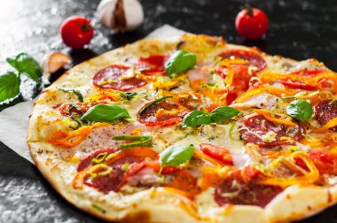 Pizza Mozzarella peyniri, jambon, domates, salam, biber, biber baharat ve taze fesleğen. İtalyan pizza. Yakın çekim.