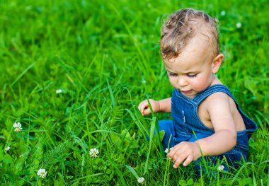 Şirin bebek çocuk parkı yeşil çimenlerin üzerinde oturan