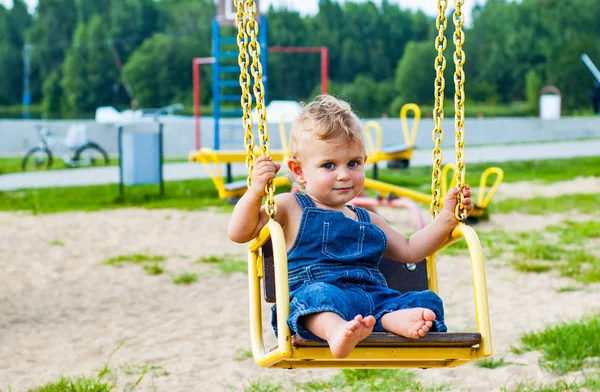 春の公園のブランコに乗る楽しみを持つ男の子 — ストック写真