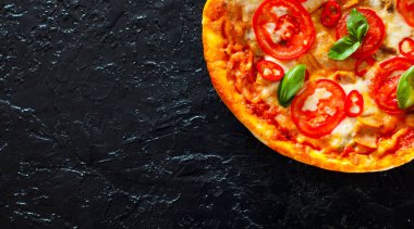 Pizza Mozzarella peyniri, jambon, domates, biber, baharat ve taze fesleğen. İtalyan pizza.on siyah arka plan. kopya alanı ile. üstten görünüm