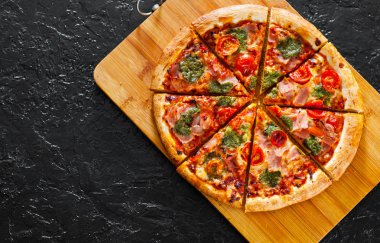 Pizza Mozzarella peyniri, jambon, domates, dilimlenmiş biber, baharatlar ve taze fesleğen pesto sos. İtalyan pizza.on siyah arka plan. kopya alanı ile. üstten görünüm