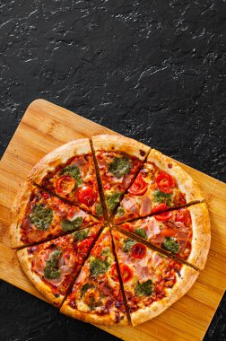 Pizza Mozzarella peyniri, jambon, domates, dilimlenmiş biber, baharatlar ve taze fesleğen pesto sos. İtalyan pizza.on siyah arka plan. kopya alanı ile. üstten görünüm
