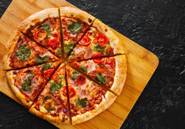 Pizza Mozzarella peyniri, jambon, domates, dilimlenmiş biber, baharatlar ve taze fesleğen pesto sos. İtalyan pizza.on siyah arka plan. kopya alanı ile. üstten görünüm