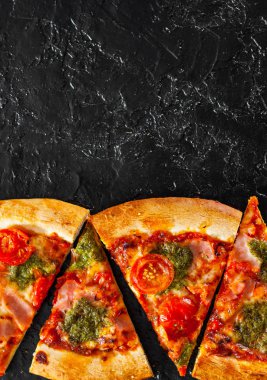 Pizza Mozzarella peyniri, jambon, domates, dilimlenmiş biber, baharatlar ve taze fesleğen pesto sos. İtalyan pizza.on siyah arka plan. kopya alanı ile. üstten görünüm