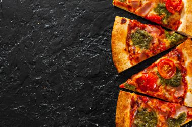 Pizza Mozzarella peyniri, jambon, domates, dilimlenmiş biber, baharatlar ve taze fesleğen pesto sos. İtalyan pizza.on siyah arka plan. kopya alanı ile. üstten görünüm