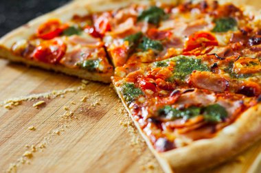 Pizza Mozzarella peyniri, jambon, domates, dilimlenmiş biber, baharatlar ve taze fesleğen pesto sos. İtalyan pizza.