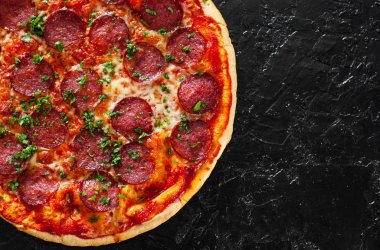 Pepperoni Pizza Mozzarella peyniri, salam, domates, biber, baharat ve taze fesleğen. Siyah arka plan üzerine İtalyan pizza. kopya alanı ile. üstten görünüm