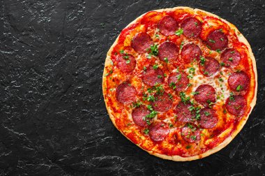 Pepperoni Pizza Mozzarella peyniri, salam, domates, biber, baharat ve taze fesleğen. Siyah arka plan üzerine İtalyan pizza. kopya alanı ile. üstten görünüm