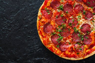 Pepperoni Pizza Mozzarella peyniri, salam, domates, biber, baharat ve taze fesleğen. Siyah arka plan üzerine İtalyan pizza. kopya alanı ile. üstten görünüm