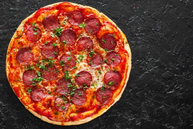 Pepperoni Pizza Mozzarella peyniri, salam, domates, biber, baharat ve taze fesleğen. Siyah arka plan üzerine İtalyan pizza. kopya alanı ile. üstten görünüm