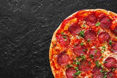 Pepperoni Pizza Mozzarella peyniri, salam, domates, biber, baharat ve taze fesleğen. Siyah arka plan üzerine İtalyan pizza. kopya alanı ile. üstten görünüm