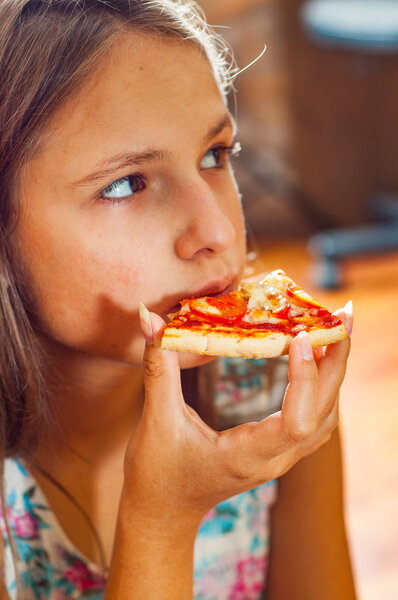 young teenager brunette girl eating a piece of pizza