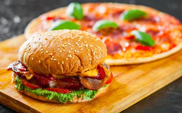 牛肉のパテ トマト オニオン ベーコン チーズ バーガーとモッツァレラのピザのチーズ トマト サラミ ピーマン ペパロニのスパイスと新鮮なバジル — ストック写真