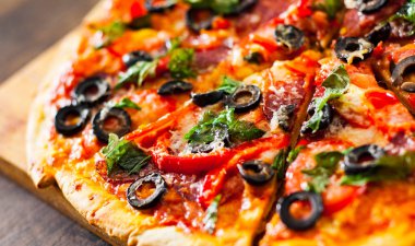 dilim Pizza Mozzarella peyniri, salam, biber, biber, domates, zeytin, baharat ve taze fesleğen. Ahşap arka plan üzerinde İtalyan pizza