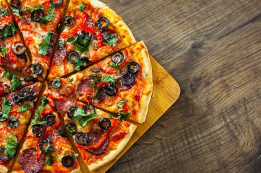 dilim Pizza Mozzarella peyniri, salam, biber, biber, domates, zeytin, baharat ve taze fesleğen. Ahşap arka plan üzerinde İtalyan pizza