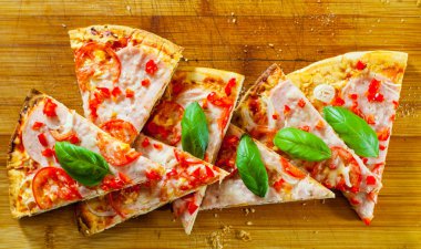 Pizza Mozzarella peyniri, jambon, domates, dilimlenmiş biber, baharatlar ve taze fesleğen. Ahşap arka plan üzerinde İtalyan pizza.