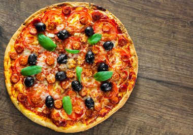 Pizza Mozzarella peyniri, salam, biber, biber, domates, zeytin, baharat ve taze fesleğen. İtalyan pizza ahşap arka plan üzerinde. kopya alanı ile. üstten görünüm