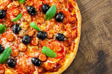 Pizza Mozzarella peyniri, salam, biber, biber, domates, zeytin, baharat ve taze fesleğen. İtalyan pizza ahşap arka plan üzerinde. kopya alanı ile. üstten görünüm