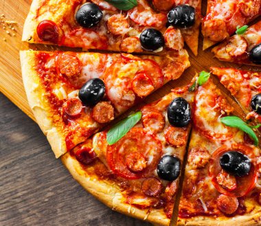 dilim Pizza Mozzarella peyniri, salam, biber, biber, domates, zeytin, baharat ve taze fesleğen. Ahşap arka plan üzerinde İtalyan pizza