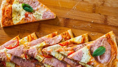 Pizza Mozzarella peyniri, jambon, domates, dilimlenmiş biber, baharatlar ve taze fesleğen. Ahşap arka plan üzerinde İtalyan pizza