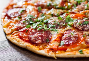 dilimlenmiş Pepperoni Pizza Mozzarella peyniri, salam, domates, biber, baharat ve taze fesleğen. Ahşap arka plan üzerinde İtalyan pizza
