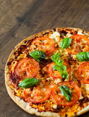 Pizza Mozzarella peyniri, domates, biber, baharat ve taze fesleğen. İtalyan pizza. Pizza Margherita veya Margarita. ahşap arka plan üzerinde