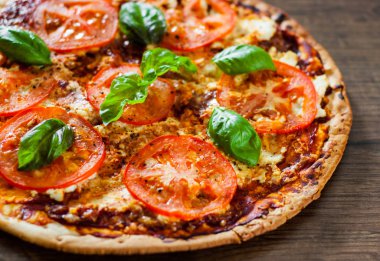 Pizza Mozzarella peyniri, domates, biber, baharat ve taze fesleğen. İtalyan pizza. Pizza Margherita veya Margarita. ahşap arka plan üzerinde