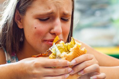 Genç Genç kız portresi hamburger yiyin. Kız hızlı yemek yemeye çalışıyor