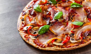 Pizza Mozzarella peyniri, mantar, pastırma, domates, biber, baharat ve taze fesleğen. Ahşap arka plan üzerinde İtalyan pizza.