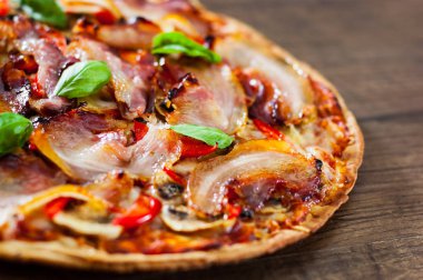 Pizza Mozzarella peyniri, mantar, pastırma, domates, biber, baharat ve taze fesleğen. Ahşap arka plan üzerinde İtalyan pizza.