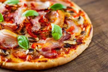 Pizza Mozzarella peyniri, mantar, pastırma, domates, biber, baharat ve taze fesleğen. Ahşap arka plan üzerinde İtalyan pizza.