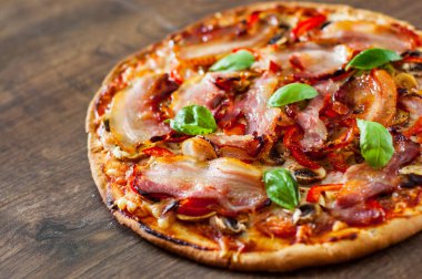 Pizza Mozzarella peyniri, mantar, pastırma, domates, biber, baharat ve taze fesleğen. Ahşap arka plan üzerinde İtalyan pizza.