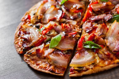 Pizza dilimlenmiş Mozzarella peyniri, mantar, pastırma, domates, biber, baharat ve taze fesleğen. Ahşap arka plan üzerinde İtalyan pizza.