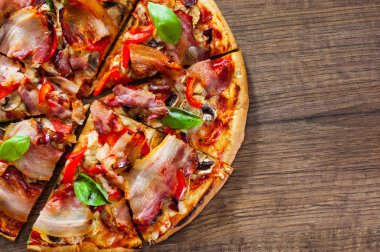 Pizza dilimlenmiş Mozzarella peyniri, mantar, pastırma, domates, biber, baharat ve taze fesleğen. Ahşap arka plan üzerinde İtalyan pizza.