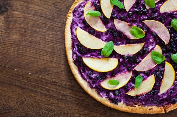 sweet pizza with ricotta cheese, blueberry and slices apple. dessert pizza on a wooden background