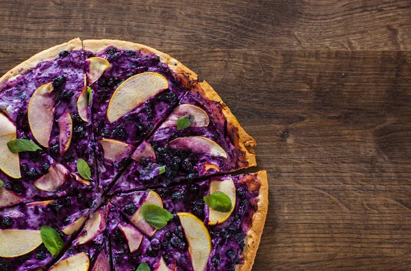 sweet pizza with ricotta cheese, blueberry and slices apple. dessert pizza on a wooden background