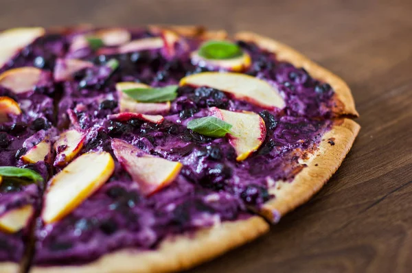 sweet pizza with ricotta cheese, blueberry and slices apple. dessert pizza on a wooden background