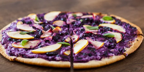 sweet pizza with ricotta cheese, blueberry and slices apple. dessert pizza on a wooden background