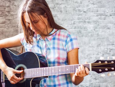 genç genç gri duvar arka plan üzerinde siyah akustik gitar çalmaya uzun saçlı esmer kız portresi