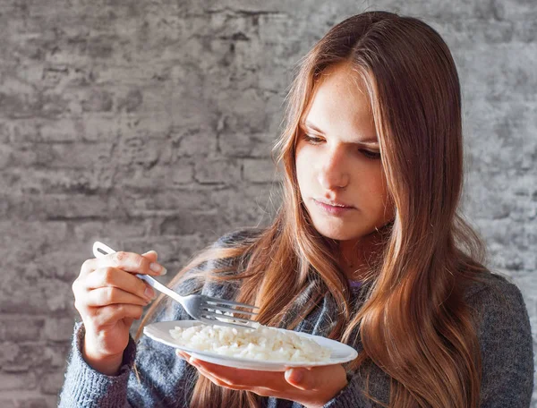 灰色の壁の背景にご飯を食べて長い髪の 代の若いブルネットの少女の肖像画 — ストック写真