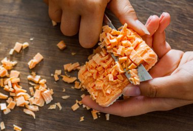 Ahşap arka plan üzerinde küpler halinde bir bıçak kesim sabunla eller.