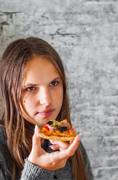 若いですティーンブルネット女の子とともに長いです髪食べるスライスのピザの灰色の壁の背景 — ストック写真