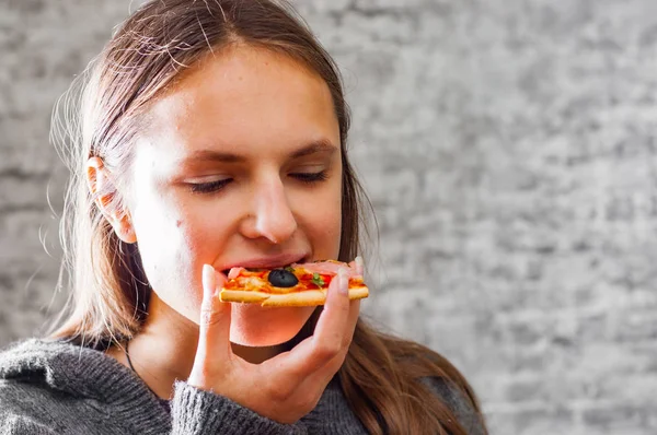 若いですティーンブルネット女の子とともに長いです髪食べるスライスのピザの灰色の壁の背景 — ストック写真