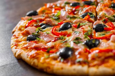 dilim Pizza Mozzarella peyniri, jambon, biber, et, domates, zeytin, baharat ve taze fesleğen. Ahşap arka plan üzerinde İtalyan pizza