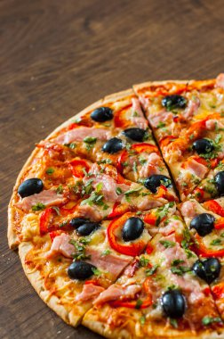 dilim Pizza Mozzarella peyniri, jambon, biber, et, domates, zeytin, baharat ve taze fesleğen. Ahşap arka plan üzerinde İtalyan pizza