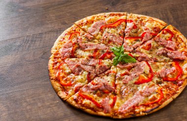 dilim Pizza Mozzarella peyniri, jambon, biber, et, domates, baharat ve taze fesleğen. Ahşap arka plan üzerinde İtalyan pizza