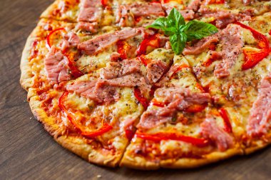 dilim Pizza Mozzarella peyniri, jambon, biber, et, domates, baharat ve taze fesleğen. Ahşap arka plan üzerinde İtalyan pizza