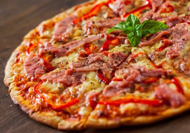 dilim Pizza Mozzarella peyniri, jambon, biber, et, domates, baharat ve taze fesleğen. Ahşap arka plan üzerinde İtalyan pizza