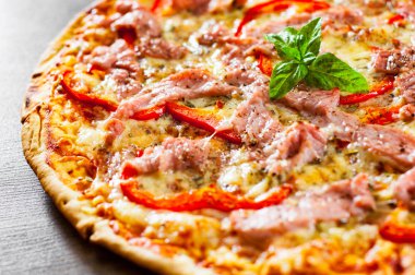 Pizza Mozzarella peyniri, jambon, biber, et, domates, baharat ve taze fesleğen. Ahşap arka plan üzerinde İtalyan pizza